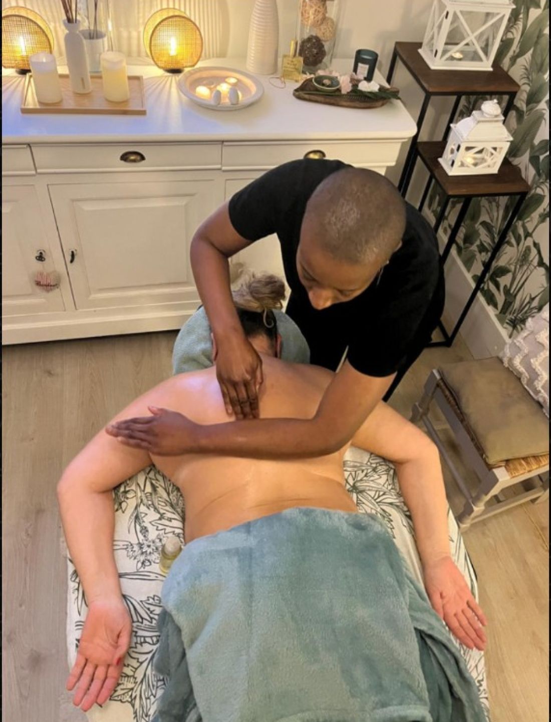 Massage du dos à l’huile, vu du dessus, avec un linge vert d’eau.